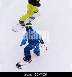 Vue arrière du père avec enfant sur le snowboard, la piste de ski. Loisirs d'hiver, style de vie sportif, entraînement au ski et vacances familiales en plein air Banque D'Images