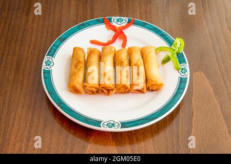 Rouleaux croquants chinois impériaux frits dans de l'huile d'olive sur une assiette blanche Banque D'Images