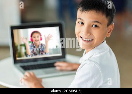 Un garçon heureux rencontre son camarade de classe en ligne avec un ordinateur portable. Banque D'Images