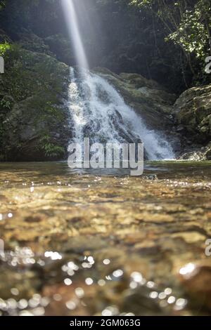 Magnifique plan vertical d'une chute d'eau tombant sur des rochers, puis dans un petit lac Banque D'Images