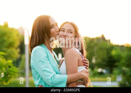 Mère Kissing sur joue souriante fille Teen. Profiter du moment et s'amuser ensemble. Portrait franc des adolescentes et des adolescents. Concept de personnes réelles Banque D'Images