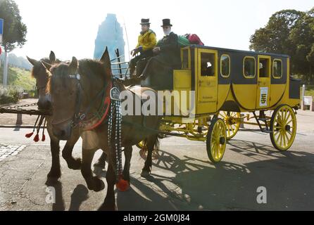 14 septembre 2021, Saxe, Leipzig: Le Coachman Siegfried Händler commence son voyage vers Dresde devant le Monument de la bataille des Nations avec sa stagecoach historique, sur laquelle l'un des neuf passagers a pris place sur la boîte à autocars à côté de lui. La calèche jaune, réplique de 1830, est tirée par les chevaux à sang froid 'Evi' et 'Frau Krause' et a de la place pour 9 personnes. L'offre inhabituelle de la compagnie d'autocars Händler à Bad Düben vise à donner aux voyageurs patients une compréhension de voyager comme dans le temps de Napoléon sur la route de Leipzig à Dresde sur quatre jours Banque D'Images