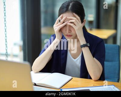 Les femmes d'affaires consciencieux qui travaillent sur son bureau et se sentent fatiguées du travail, des maux de tête, de la dépression, fatiguées de trouver des solutions pour résoudre des problèmes d'entreprise, Banque D'Images