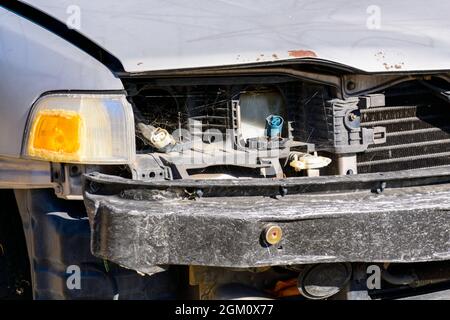 Vue avant partielle d'une vieille voiture avec un ensemble de phare, un cache de bouclier et une calandre manquants. Banque D'Images