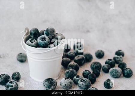 Bleuets congelés dans un petit seau sur fond de béton. Fond sain de fruits de saison biologiques. Aliments biologiques. Récolte, préparation de la nourriture pour gagner Banque D'Images