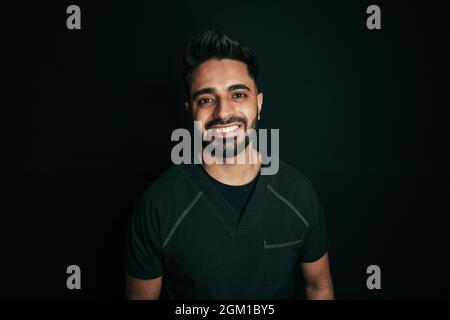 Portrait mixte race homme infirmière souriant avec des dents brillantes pour le portrait contre le dos noir Banque D'Images