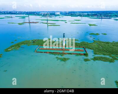 DHAKA, BANGLADESH - 16 SEPTEMBRE 2021 : vue aérienne d'un Chimney depuis la fabrique de briques locale inondée par les pluies de mousson près de Savar, Dhaka, Bangladesh. Des centaines d'usines de briques semblent avoir presque disparu sous l'eau à la suite de graves inondations. Les bâtiments ont été couverts d'eau en raison de fortes pluies pendant toute la saison de la mousson. Les travailleurs ont pu sauver des milliers de briques, mais beaucoup ont été perdus dans les eaux profondes de 20 pieds. Le 16 septembre 2021 à Dhaka, au Bangladesh. (Photo de Mustasinur Rahman Alvi/ Eyepix Group) Banque D'Images