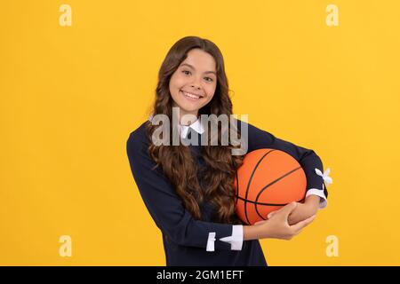 un enfant souriant tient le ballon de basket-ball sur fond jaune, basket-ball Banque D'Images