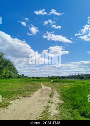 Belle vue sur le chemin dans le parc, herbe verte, ciel bleu avec des nuages blancs par une chaude journée ensoleillée Banque D'Images