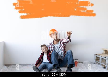 Une jeune famille heureuse est en train de rénover sa maison, le père tient son fils assis sur le sol. Gémissement blanc avec espace pour le texte. Banque D'Images