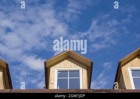 Photo conceptuelle de la maison avec des dortoirs en bois d'époque sur le toit du bâtiment contre ciel bleu avec des nuages dans la vieille ville de Lituanie. Appartements esthétiques dans le grenier contre la ligne d'horizon Banque D'Images