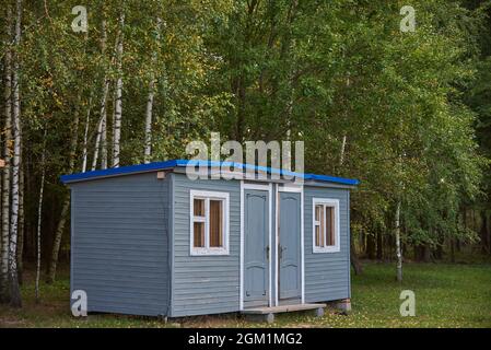 Une petite maison d'été grise se dresse dans une clairière contre le fond de bouleaux. Banque D'Images