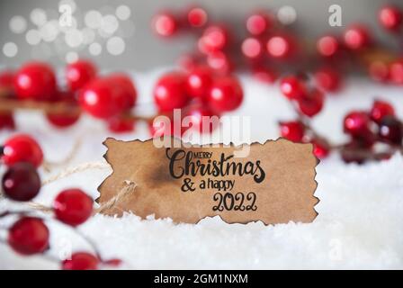 Étiquette brûlée avec la calligraphie anglaise Joyeux Noël et Un heureux 2022. Décoration de Noël rouge avec neige Banque D'Images