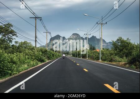 Vue sur la chaîne de montagnes verdoyantes avec poteau utilitaire et lampadaire sur l'autoroute en campagne à Sam Roi Yot, Prachuap Khiri Khan Banque D'Images