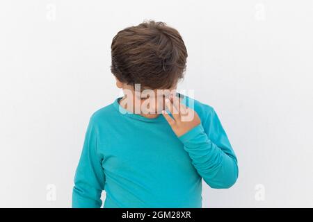 Enfant triste avec t-shirt bleu gesticalant sur un fond blanc Banque D'Images