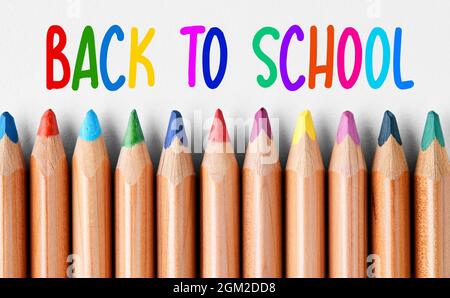 Crayons de crayon en bois colorés dans une rangée avec message de retour à l'école écrit avec des lettres colorées en haut. Banque D'Images