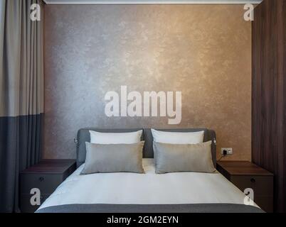 Intérieur moderne d'une chambre confortable dans l'appartement. Couleurs marron. Vue avant des oreillers sur le lit king size. Banque D'Images
