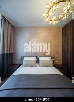 Intérieur moderne d'une chambre confortable dans l'appartement. Couleurs marron. Vue avant des oreillers sur le lit king size. Banque D'Images