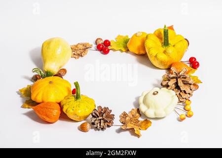 Couronne d'automne de citrouilles, de cônes, de noix, de feuilles d'automne et de baies isolées sur fond blanc. Composition créative de la pose à plat, faite à la main. Décoration d'intérieur Banque D'Images