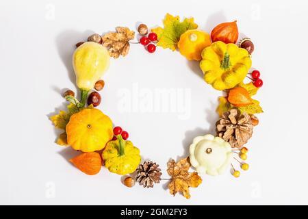 Couronne d'automne de citrouilles, de cônes, de noix, de feuilles d'automne et de baies isolées sur fond blanc. Composition créative de la pose à plat, faite à la main. Décoration d'intérieur Banque D'Images