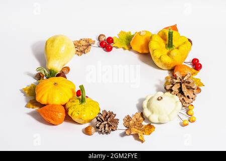 Couronne d'automne de citrouilles, de cônes, de noix, de feuilles d'automne et de baies isolées sur fond blanc. Composition créative de la pose à plat, faite à la main. Décoration d'intérieur Banque D'Images