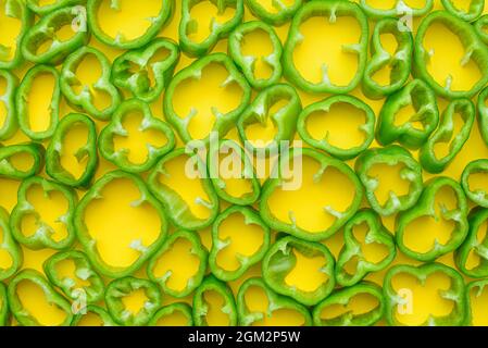 Vue de dessus des poivrons verts tranchés sur fond jaune Banque D'Images