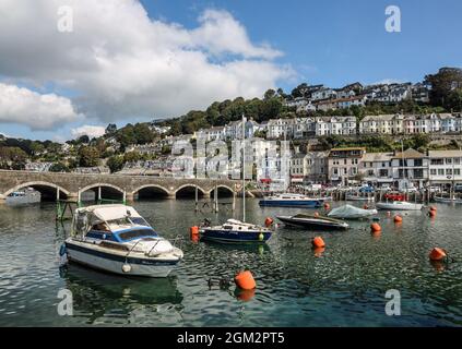 Des bateaux de toutes sortes ont amarré près du pont au-dessus de la rivière Looe dans les Cornouailles avec des boutiques et des cafés à East Looe formant une toile de fond. Banque D'Images