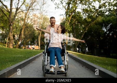 Couple amoureux joyeux avec promenades en fauteuil roulant dans le parc Banque D'Images