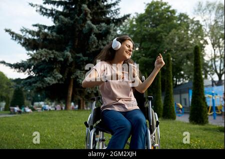 Une femme handicapée en fauteuil roulant écoute de la musique Banque D'Images