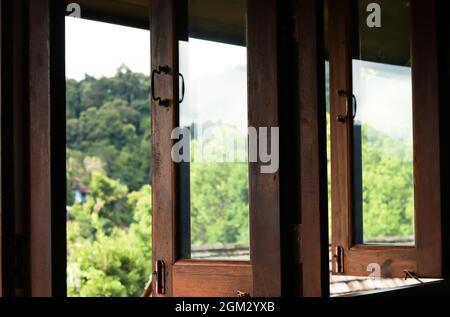 Fenêtre en bois brun foncé ouverte et à l'extérieur est flou paysage de montagne verte. Banque D'Images