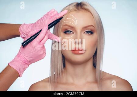 Belle femme blonde avec des marques pour la chirurgie plastique sur son visage Banque D'Images