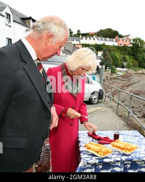 Le prince de Galles et la duchesse de Cornouailles, connu sous le nom de duc et duchesse de Rothesay quand en Écosse, essayez quelques poissons et chips locaux, lors de leur visite à Portree, dans l'île de Skye, dans les Highlands d'Écosse, pour voir comment les entreprises vont de l'avant après le verrouillage du coronavirus. Date de la photo : jeudi 16 septembre 2021. Banque D'Images