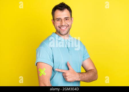 Photo de l'optimiste brunet homme point main plâtre porter des lunettes t-shirt bleu isolé sur fond jaune Banque D'Images