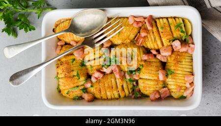Pommes de terre cuites au four avec jambon, herbes et chapelure sur fond gris clair. Cuisine scandinave. Vue de dessus. Banque D'Images