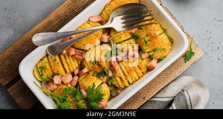 Pommes de terre cuites au four avec jambon, herbes et chapelure sur fond gris clair. Cuisine scandinave. Vue de dessus. Banque D'Images