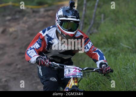 Un gros plan d'un jeune motard de montagne descendant dans les bois lors d'une course Banque D'Images