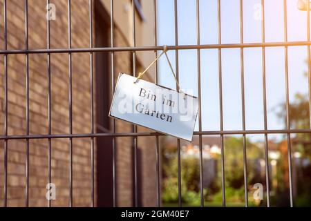 Panneau sur une clôture de jardin avec l'inscription Bin im Garten (je suis dans le jardin) Banque D'Images