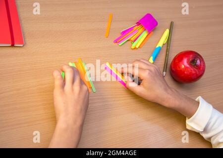 Un étudiant sur un bureau étudie les mathématiques avec des bâtons. Un écolier effectue une tâche sur le lieu de travail. Le concept de l'éducation, de l'enseignement des connaissances, des compétences et des capacités des enfants. Banque D'Images