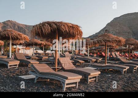 Vue sur les parasols en chaume sur la plage et les chaises longues sous eux Banque D'Images