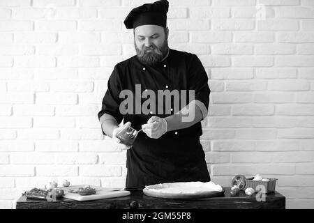 Chef chef barbu prépare des repas à la table dans la cuisine Banque D'Images