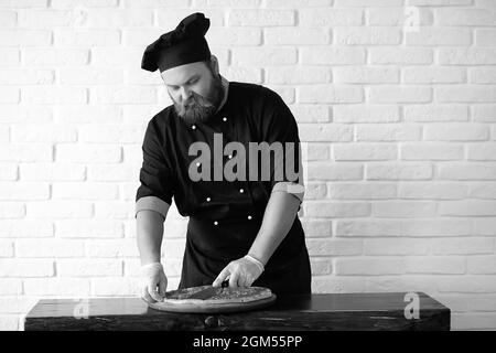 Chef chef barbu prépare des repas à la table dans la cuisine Banque D'Images