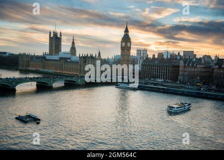 Londres, Royaume-Uni, vue sur les gratte-ciel au coucher du soleil avec des monuments célèbres, Big Ben, le Parlement et des navires sur la Tamise avec un magnifique ciel bleu et jaune. Banque D'Images