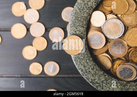 Bol avec pièces de monnaie dorées sur fond de bois sombre Banque D'Images