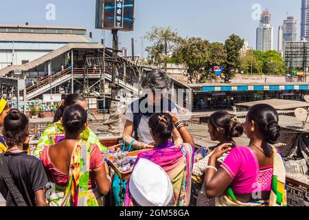 Mumbai, Maharashtra, Inde : les vendeurs de souvenirs encerclent un touriste occidental près de Dhobi Ghat à la voie de passage de la gare de Mahalaxmi. Dhobi Ghat est un ver Banque D'Images