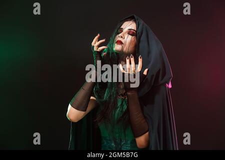 Belle femme habillée comme sorcière pour Halloween partie sur fond sombre Banque D'Images