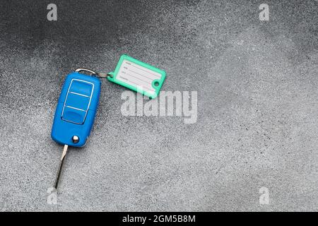 Clé de voiture bleue avec étiquette en plastique sur fond de gringe Banque D'Images