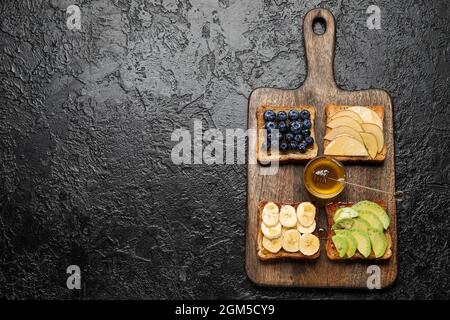 Délicieux pain grillé au miel et aux fruits sur fond noir Banque D'Images