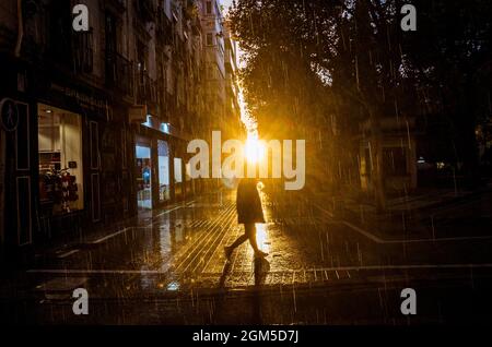 Rétroéclairé d'un homme marchant au coucher du soleil par temps pluvieux. Grenade, Espagne. Banque D'Images