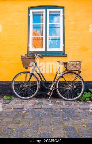 Vélo stationné près du mur jaune d'une vieille maison Banque D'Images