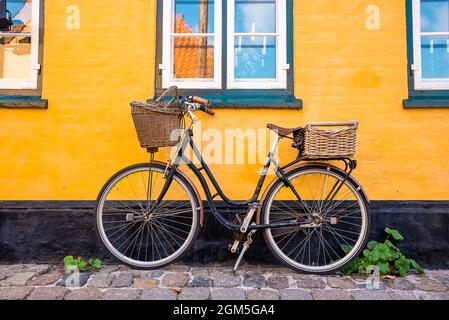 Vélo stationné près du mur jaune d'une vieille maison Banque D'Images
